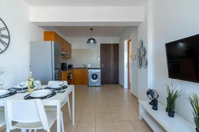 a kitchen and living room with a white table and chairs at Polyn 1- Bedroom Apartment in Larnaca in Larnaka