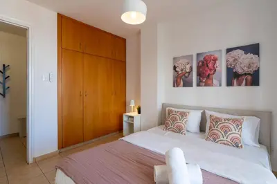 a bedroom with a large bed and a wooden cabinet at Polyn 1- Bedroom Apartment in Larnaca in Larnaka