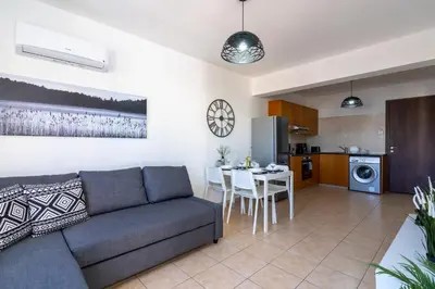 a living room and kitchen with a couch and a table at Polyn 1- Bedroom Apartment in Larnaca in Larnaka