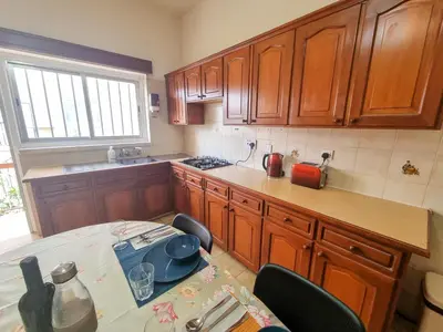 a kitchen with wooden cabinets and a table with a tableablish at Luxury City Rooms - Smart TV with Netflix in Larnaka