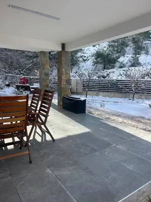 a patio with two chairs and a table and snow at DIAMOND Stone Wooden Guest House in Khandria