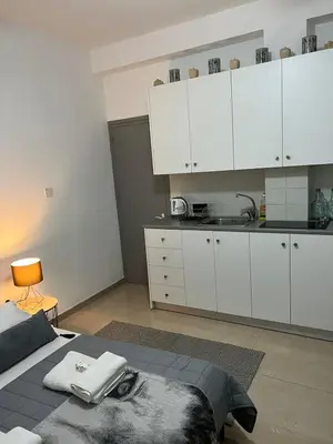 a bedroom with a bed and a kitchen with white cabinets at HESTIA Studio Downtown Nicosia in Nicosia