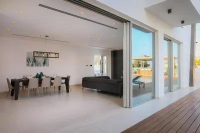 a dining room and living room with sliding glass doors at Cove Seaview Villas - Neptune in Ayia Napa