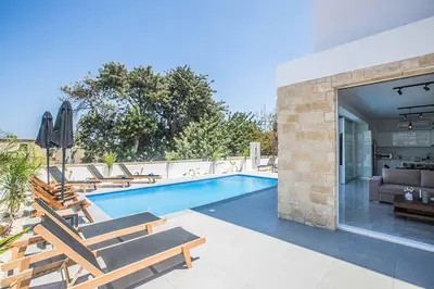 a swimming pool with chairs and a living room at Vie Blue 4 in Protaras