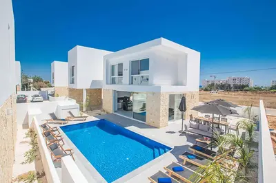 a large white house with a swimming pool and chairs at Vie Bleu 1 in Protaras