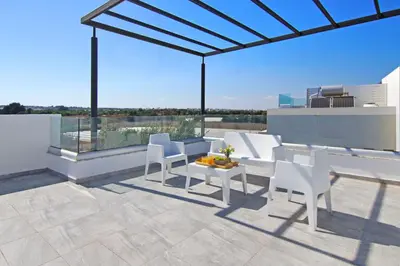 a patio with white chairs and a table with a view at Queen Lydia in Protaras