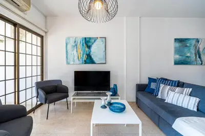 a living room with a blue couch and a tv at Azure 2-BR W/Terrace in Larnaca in Larnaka