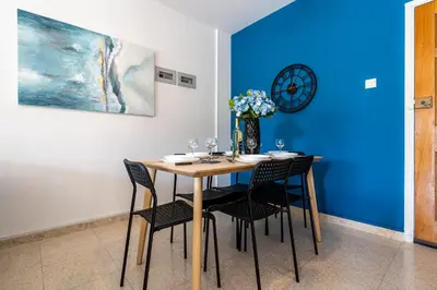 a dining room table with chairs and a clock on the wall at Azure 2-BR W/Terrace in Larnaca in Larnaka