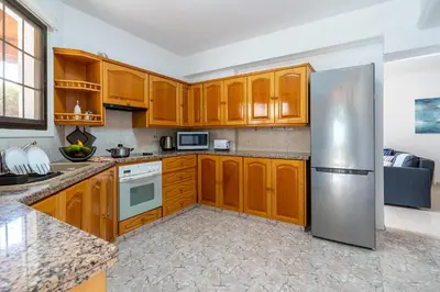 a kitchen with wooden cabinets and a stainless steel refrigerator at Azure 2-BR W/Terrace in Larnaca in Larnaka