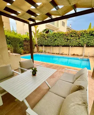 a patio with a white table and chairs and a pool at El Soleo Luxury Villa in Limassol