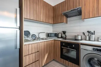 a small kitchen with wooden cabinets and a dishwasher at Sunflower 1-Bedroom Apartment in Larnaca in Larnaka