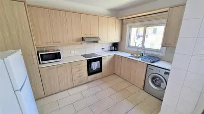 a kitchen with wooden cabinets and a washer and dryer at Comfy and Exquisite ROOMS in a Shared 3BR Apartment Near Main Harbor, City Center in Larnaka