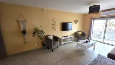 a living room with a couch and a tv on the wall at Comfy and Exquisite ROOMS in a Shared 3BR Apartment Near Main Harbor, City Center in Larnaka