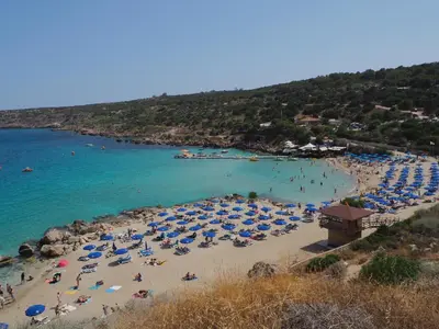 a beach with umbrellas and people in the water at Mosaic villa by the sea in Protaras