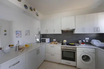 a kitchen with white cabinets and a stove top oven at Melis Villa - Charming villa in Central Protaras in Protaras