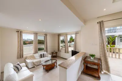a living room with white furniture and large windows at Protaras Posidon By The Sea in Protaras