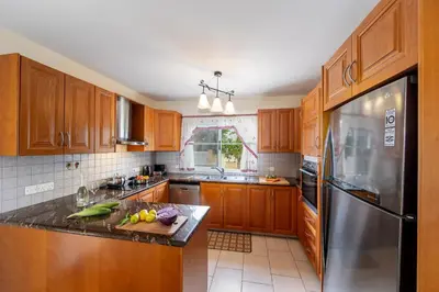 a kitchen with wooden cabinets and a stainless steel refrigerator at Protaras Posidon By The Sea in Protaras
