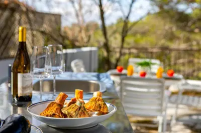 a bowl of food on a table with a bottle of wine at Platres Forty Pine Trees Cottage in Platres