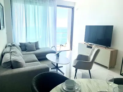 a living room with a couch and a tv at Del Mar Beachfront Boutique Residence in Limassol