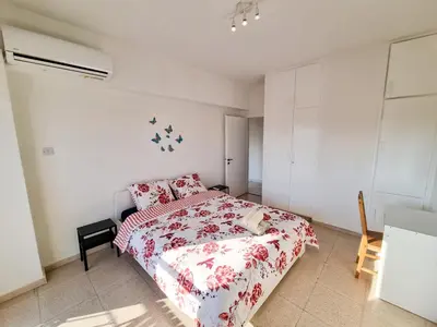 a bedroom with a bed with a red and white comforter at City View Rooms in Larnaka