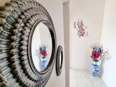 a mirror on a wall with a vase of flowers at City View Rooms in Larnaka