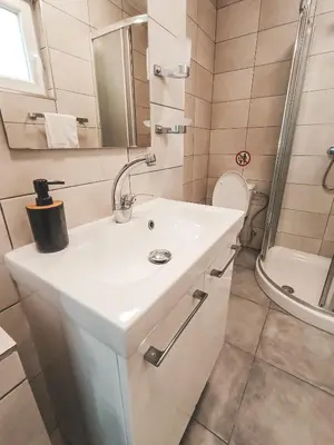 a bathroom with a white sink and a shower at Shelter next to the beach in Larnaka