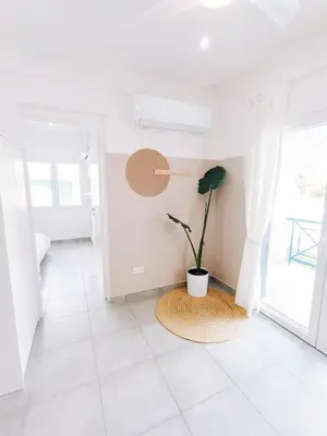 a white room with a potted plant on a tiled floor at Shelter next to the beach in Larnaka