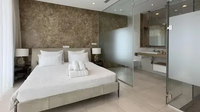 a bedroom with a large white bed and a bathroom at Vivo Mare Beachfront Villas - Seashell in Ayia Napa