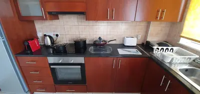 a kitchen with wooden cabinets and a stove top oven at Vasilas Holiday Apartment #2 in Larnaka