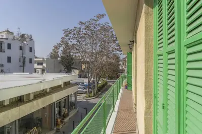 a balcony of a building with green shutters and a street at City center appartments in Nicosia