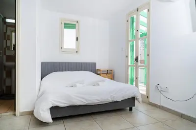 a white bedroom with a bed and a window at City center appartments in Nicosia