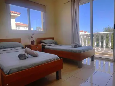 a bedroom with two beds and a large window at Nissi Beach Golden Villas in Ayia Napa