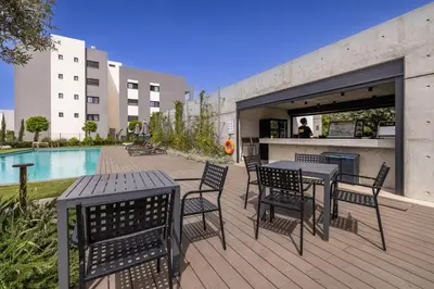 a deck with tables and chairs next to a pool at Sunset Gardens in Limassol