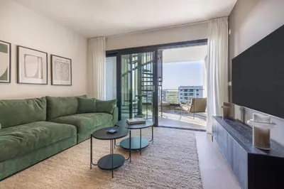 a living room with a green couch and two tables at Sunset Gardens in Limassol