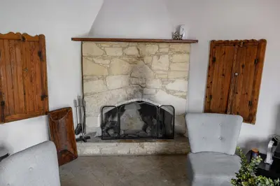 a living room with a stone fireplace with two chairs at Omodos vintage houses in Omodos