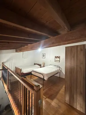 a bedroom with a bed and a wooden staircase at King's house in Lofou