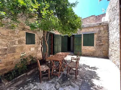 a wooden table and chairs in front of a building at King's house in Lofou
