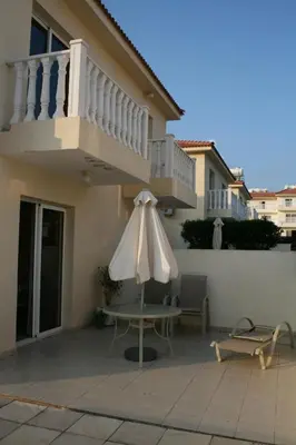 a patio with a table and an umbrella in front of a house at Nissi Villa in Ayia Napa