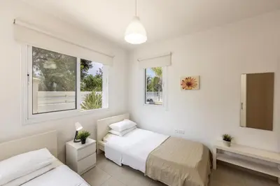 a bedroom with two beds and two windows at Flouressia Gardens Villas in Protaras