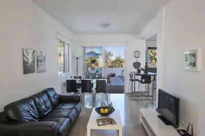 a living room with a black leather couch and a tv at Flouressia Gardens Villas in Protaras