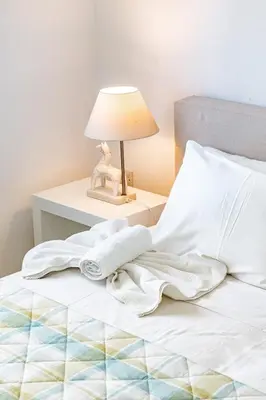 a bed with white sheets and a lamp on a table at Villa Elliana by Ezoria Villas in Protaras