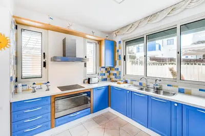 a kitchen with blue cabinets and windows at Villa Elliana by Ezoria Villas in Protaras