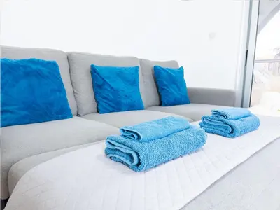 a couch with blue pillows and blue towels on it at Pandora Holiday Apartment Ayia Napa in Ayia Napa