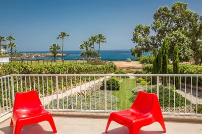 two red chairs sitting on a balcony looking at the ocean at Villa Mesogeios ME16 in Protaras