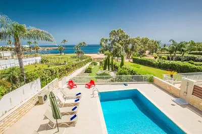 a swimming pool with chairs and the ocean in the background at Villa Mesogeios ME16 in Protaras