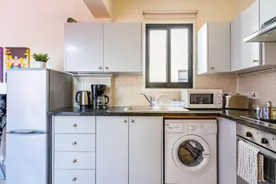 a kitchen with white cabinets and a washer and dryer at Freya 1-Bedroom Apartment in Larnaca in Larnaka