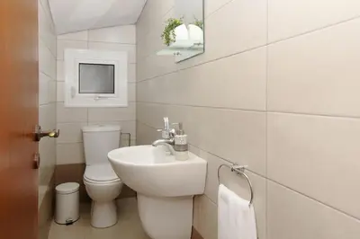 a white bathroom with a toilet and a sink at Villa Clara in Protaras