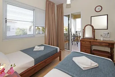 a bedroom with two beds and a table and a mirror at Villa Clara in Protaras