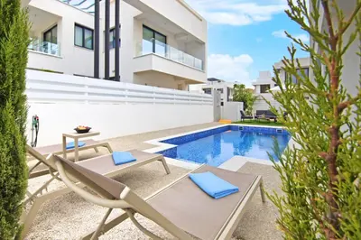 a patio with two chairs and a swimming pool at Villa Amity in Protaras