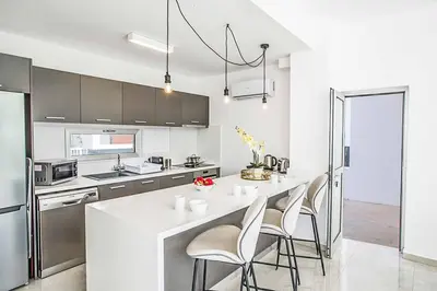 a kitchen with a white counter and chairs in it at Olivine Pearl OL21 in Protaras